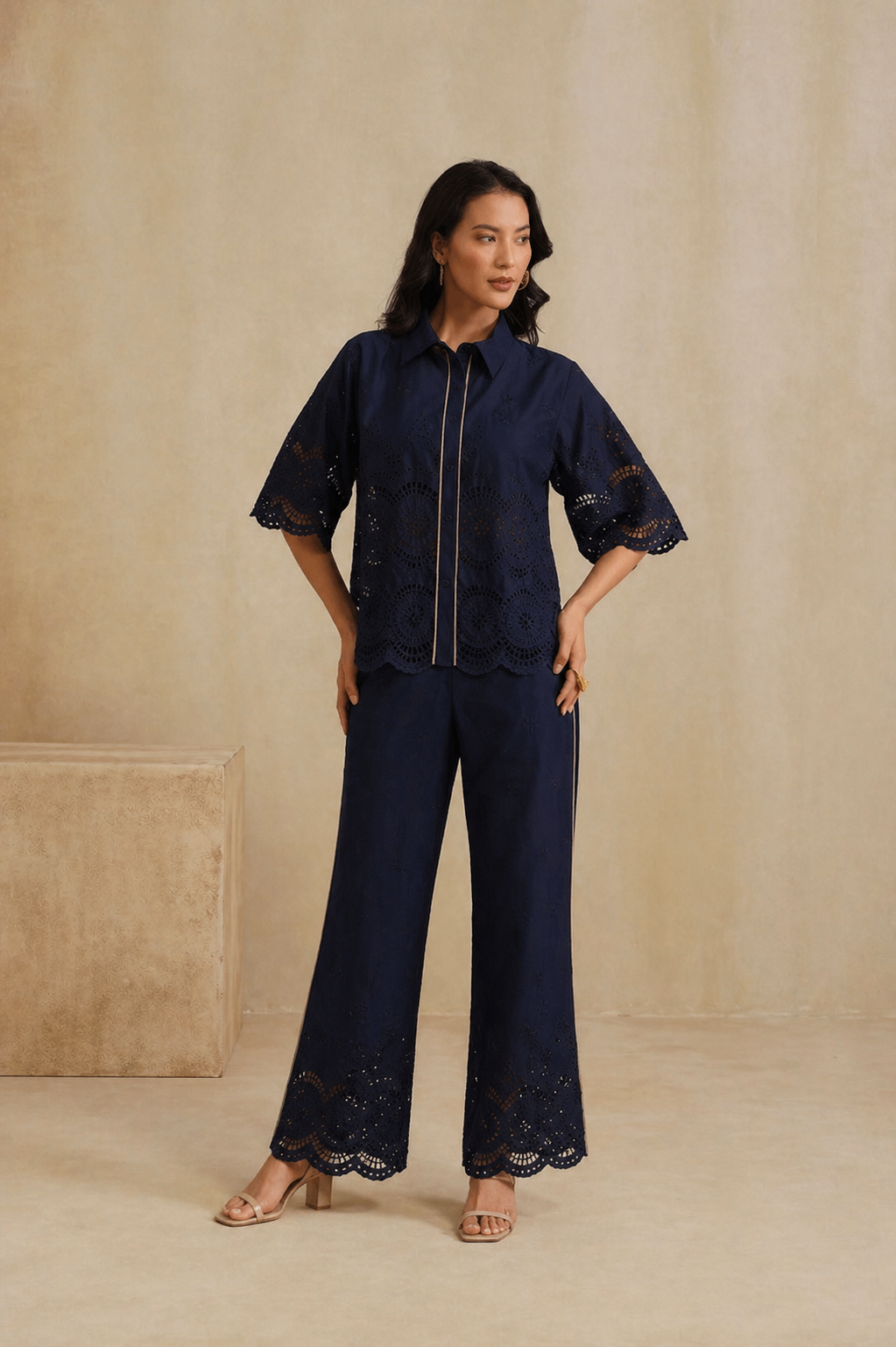 Woman wearing a navy blue outfit with lace details against a beige background